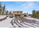 Inviting home showcasing a large driveway with a car, nestled amidst a snowy and wooded landscape at 27987 Pine Grove Trl, Conifer, CO 80433