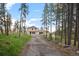 Charming two-story home with a long driveway surrounded by lush trees and natural landscaping at 27987 Pine Grove Trl, Conifer, CO 80433