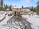 Charming home features a spacious driveway and a well-maintained exterior in a snowy landscape at 27987 Pine Grove Trl, Conifer, CO 80433