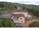 Tan two-story home featuring a rear deck, walkout patio, and a backdrop of dense trees and serene mountain views at 27987 Pine Grove Trl, Conifer, CO 80433