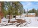 View of large outbuilding and storage shed with snow covered ground and mature pines at 27987 Pine Grove Trl, Conifer, CO 80433