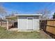A grey utility shed with a covered lean-to on a grassy lot with a wooden fence at 4290 S Cherokee St, Englewood, CO 80110