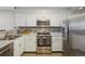 Well-lit kitchen featuring stainless steel appliances, white cabinets, and granite countertops at 1818 S Quebec Way # 11-3, Denver, CO 80231