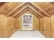 Unfinished attic with wooden beams, a door, and white flooring at 23039 Isoleta Rd, Indian Hills, CO 80454