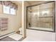 Combined bathtub and shower with glass door, window, toilet, towel holder, and tiled walls at 23039 Isoleta Rd, Indian Hills, CO 80454