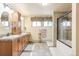 Tiled bathroom with double vanity, framed mirrors, drawers, and combined bathtub and shower with glass door at 23039 Isoleta Rd, Indian Hills, CO 80454