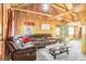 Spacious living room with a large leather couch, wooden walls, and a rustic wood ceiling at 23039 Isoleta Rd, Indian Hills, CO 80454
