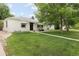 Well-kept front yard of a white bungalow with a sidewalk, mature trees, and seating area at 1852 S Elm St, Denver, CO 80222