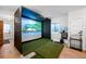 Home golf simulator setup with screen, putting green and equipment storage at 2821 E Cedar Ave # 2, Denver, CO 80209