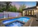 Beautiful pool and hot tub area with vibrant blue lighting, a stone wall, and lush greenery at 2821 E Cedar Ave # 2, Denver, CO 80209