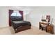 Cozy bedroom with dark wood bed frame, vanity and matching stool, carpet floor, and window with red curtains at 4125 Marble Dr, Longmont, CO 80504
