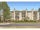Three-story tan apartment building with multiple balconies, trimmed lawn, and asphalt road at 481 S Kalispell Way # 205, Aurora, CO 80017