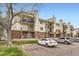 Multi-level condo building with balconies and brick accents, with a tree in the foreground at 481 S Kalispell Way # 205, Aurora, CO 80017