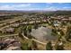 Wide aerial view of a community with a pond, swimming pool, and winding trails on a sunny day at 5069 Castle Pines S Dr, Castle Rock, CO 80108