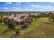 Beautiful aerial view of several brown homes with tile roofs and green lawns on a sunny day at 5069 Castle Pines S Dr, Castle Rock, CO 80108