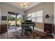 Elegant music room with a grand piano, stylish rug, and natural light from the sliding glass doors and window at 5069 Castle Pines S Dr, Castle Rock, CO 80108