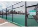 Close up of the community tennis court featuring a green court, black fencing, and court rules sign at 10330 E Jewell Ave # 67, Aurora, CO 80247