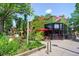 Exterior building shot with red umbrellas, green brick and outdoor seating at 1141 Adams St, Denver, CO 80206