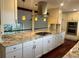 A modern kitchen with a large island, a cooktop, modern appliances, and beautiful pendant lights at 7906 W Walker Dr, Littleton, CO 80123