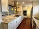 A chef's kitchen with white cabinetry, stainless steel appliances, hardwood floors and a large island with cooktop at 7906 W Walker Dr, Littleton, CO 80123