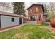 Backyard featuring gray garage, small grassy area, patio and brick house at 2568 Clermont St, Denver, CO 80207