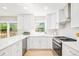 Bright, white kitchen with stainless steel appliances, tile backsplash, quartz countertops, and hardwood floors at 16438 E Prentice Cir, Centennial, CO 80015