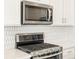 A stainless steel microwave sits above a modern stove with beautiful white backsplash at 17417 E 89Th Way, Commerce City, CO 80022