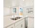 Modern kitchen island with stainless steel dishwasher, sink, and white cabinets and countertops at 17417 E 89Th Way, Commerce City, CO 80022