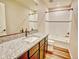 Well-lit bathroom features granite countertop and shower/tub combination with a white tiled surround at 885 Hearthstone Ave, Brighton, CO 80601