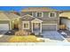 Charming home features stone accents, gray siding, a two-car garage, and manicured lawn at 885 Hearthstone Ave, Brighton, CO 80601