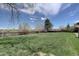 A large, grassy backyard surrounded by a wooden privacy fence and mature trees and other landscaping at 14993 W 55Th Dr, Golden, CO 80403