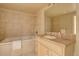 A cozy bathroom featuring a tub with tile surround, vanity with sink and large mirror at 14993 W 55Th Dr, Golden, CO 80403