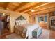 Bedroom featuring wood beams, light walls, stone fireplace, and exterior views from the large window at 11450 Marks Dr, Conifer, CO 80433