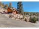 Charming home with a circular driveway, multiple garage spaces, and surrounded by lush trees and boulders at 11450 Marks Dr, Conifer, CO 80433