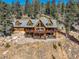 Stunning exterior elevation of a log cabin home with multiple decks, a hot tub, and views of mature trees at 11450 Marks Dr, Conifer, CO 80433