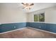 A bedroom with neutral walls, blue accent paneling, carpeted floors, and a window overlooking a green space at 3164 S Nucla St, Aurora, CO 80013