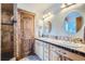Bathroom featuring double sinks, custom cabinets, and a beautifully tiled walk-in shower at 11932 Coal Creek Heights Dr, Golden, CO 80403