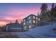 Beautiful mountain home featuring stone accents, multiple windows, and an adjacent garage under a vivid colorful sunset at 11932 Coal Creek Heights Dr, Golden, CO 80403