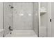 Bright bathroom showcasing a white bathtub with marble tiling and built-in storage shelves at 11021 Otis St, Westminster, CO 80020