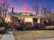 Charming brick home with a cozy front porch, a blue door, and lovely landscaping under a dramatic evening sky at 2635 N Clayton St, Denver, CO 80205