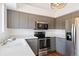 Modern kitchen featuring stainless steel appliances, gray cabinetry, and light countertops at 5402 Sweet Grass Ct, Castle Rock, CO 80109