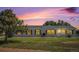 Single-story home featuring a well-maintained lawn and classic vinyl siding under a colorful sunset at 8260 County Road 39, Fort Lupton, CO 80621