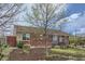 Quaint brick home featuring neat landscaping with mulch, greenery, and a welcoming bench on the lawn at 3600 Olive St, Denver, CO 80207