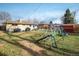 Fenced backyard with lush green grass, playset, and patio area with grills at 169 Emerald St, Broomfield, CO 80020