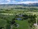 Picturesque aerial view of an estate with a tennis court, pond, and lush green surroundings with mountain views at 8000 N 41St St, Longmont, CO 80503