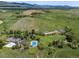 Expansive aerial view showcases a sprawling estate with tennis court, pool, and lush greenery against a mountain backdrop at 8000 N 41St St, Longmont, CO 80503