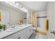 Bright bathroom features a double vanity, grey tile floor, shower with tub, and coordinated yellow accessories at 8261 Garden City Ave, Littleton, CO 80125