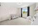 Charming Bedroom with whimsical tree decals, a pink crib, natural light, and playful decor elements at 8261 Garden City Ave, Littleton, CO 80125