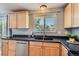 Close-up of a kitchen featuring light wood cabinetry, black countertops, and stainless steel appliances at 13483 Achilles Dr, Lone Tree, CO 80124