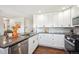 Well-lit kitchen with white cabinets, granite countertops, tile backsplash, stainless steel appliances, and hardwood floors at 3145 W Farmdale Rd, Englewood, CO 80110